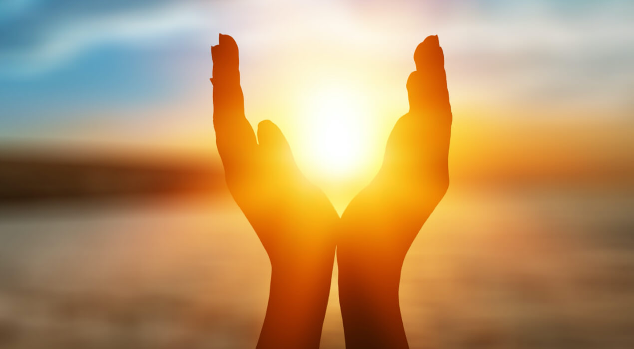 Two hands being help up to the sun