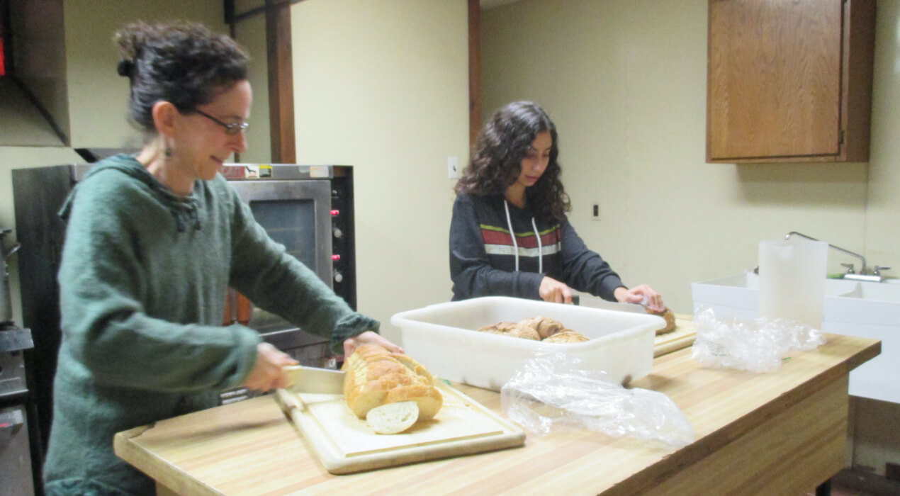 Two women cutting bread