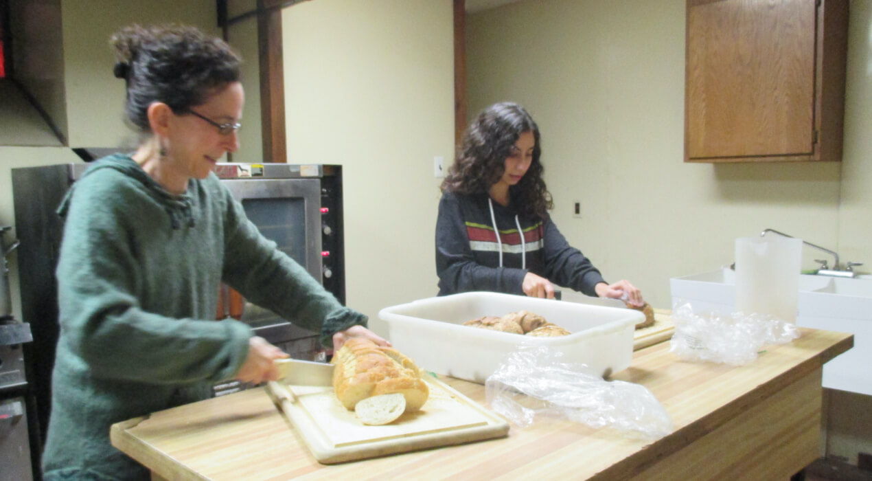 Two women cutting bread